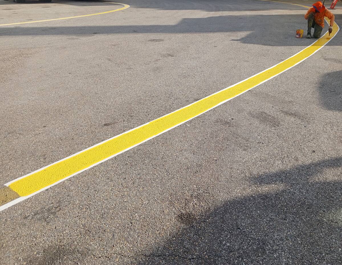 Pintura de faixa amarela com contorno branco em pátio de oficina