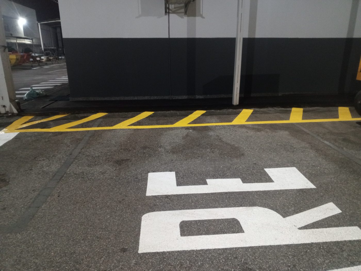 Zebrado amarelo junto à parede e sinalização PARE em pátio
